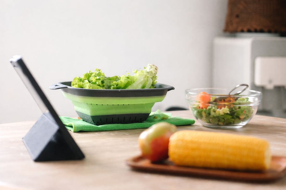 collapsible silicone colander filled with fresh vegetables on a kitchen countertop representing space-saving foldable kitchen tools
