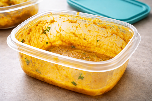 Curry-stained plastic food storage container showing yellow discoloration and leftover residue
