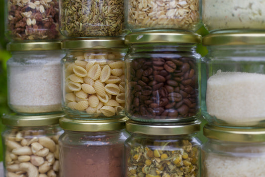 Airtight glass jars filled with dry foods like pasta, oats, coffee beans, and sugar